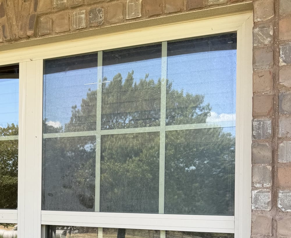 A cloudy, hard-water-stained window before cleaning